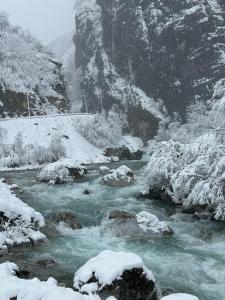 a river with snow on the side of a mountain at Guest house Hyrmet Demushi in Valbonë