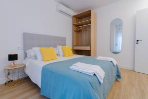 1 dormitorio con 1 cama con almohadas amarillas y blancas en Apartamentos TriBeCa Centro I, en Albacete