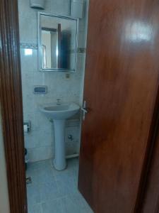 a bathroom with a sink and a wooden door at Hostal Pablito in Encarnación