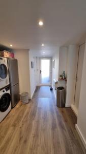 an empty living room with a kitchen and a hard wood floor at Self-contained annex, with parking. in Kent