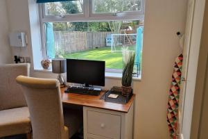 a desk with a computer on it with a window at Self-contained annex, with parking. in Kent