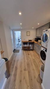 a living room with a kitchen with a wooden floor at Self-contained annex, with parking. in Kent