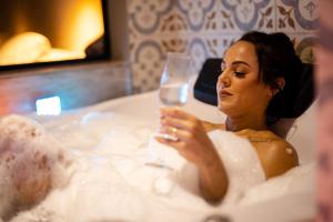 a woman sitting in a bath tub holding a wine glass at Pousada Bosque in Monte Verde