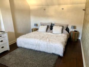 1 dormitorio con 1 cama grande con sábanas y almohadas blancas en Ferienhaus Eifel-Auszeit en Rieden