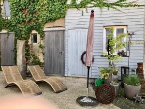 un patio con 2 sillas y una sombrilla en Ferienhaus Eifel-Auszeit en Rieden