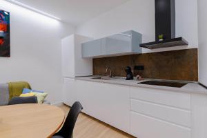 a kitchen with white cabinets and a wooden table at Apartamentos TriBeca Centro II in Albacete
