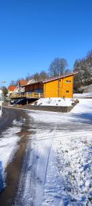 a yellow building in the snow next to a street at Felsenlandblick in Dahn
