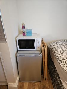 a microwave on top of a refrigerator next to a bed at Entire en-suite flat in Windsor home with free parking in Windsor