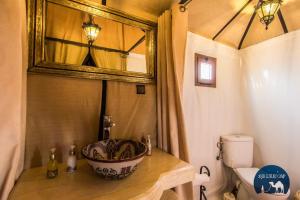 La salle de bains est pourvue d'un lavabo et d'un miroir. dans l'établissement Sahara Luxury Camp VIP, à Merzouga
