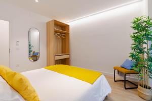 a bedroom with a bed and a chair and a mirror at Apartamentos TriBeca Centro II in Albacete