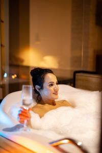 a woman sitting in a bath tub with a glass of wine at Pousada Bosque in Monte Verde