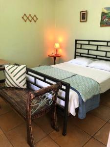 Un dormitorio con una cama grande y un banco en SERENITY BY NATURE, en Carrillos