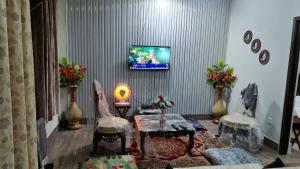 a living room with a tv on a wall at Patriata Luxury Suits in Murree