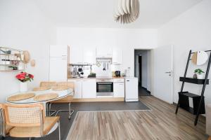 a kitchen with white cabinets and a table and chairs at RG 5 Stylish Haven-Near Brunnenmarkt in Vienna