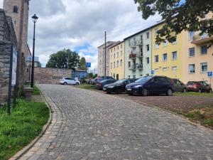 a cobblestone street with parked cars and buildings at Apartament u podnóża Gór Stołowych in Radków