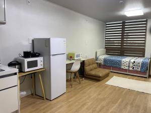 a small room with a refrigerator and a bed at Stay SonSu in Jeju