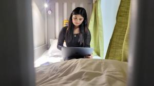 a woman sitting on a bed with a laptop at Atlantis View Hostel in Dubai