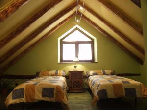 SinにあるCasa Ramón El Palléのベッド2台と窓が備わる屋根裏部屋です。