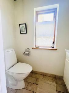 een badkamer met een wit toilet en een raam bij Mormors Gårdhus ved stranden in Rude