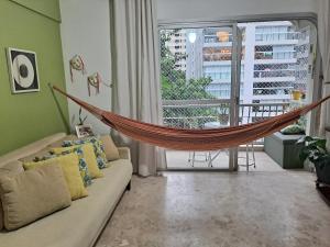 - un hamac dans le salon avec un canapé dans l'établissement Apto PITANGUEIRAS SACADA-5Min Praia 1 vaga SERV PRAIA, à Guarujá