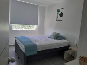 Aqualina orange Girardot في جيراردو: غرفة نوم بسرير في غرفة بيضاء