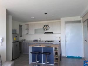 a kitchen with a island with two bar stools at Aqualina orange Girardot in Girardot