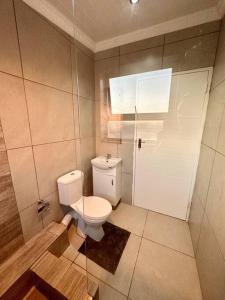een badkamer met een toilet en een glazen deur bij Fiore Apartments. in Kaapstad