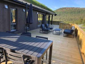 una terraza de madera con sillas, mesa y sillas en Ny og moderne hytte i Stryn. Solrik plassering, en Stryn