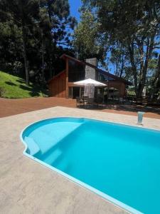 a large blue swimming pool in front of a house at Cabana das araucárias in Carlos Barbosa