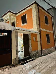 uma casa com uma porta aberta na neve em Vila Alba em Korçë
