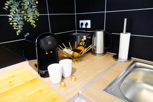 a kitchen counter with a coffee maker and cups on it at Paris I 77m Cosy I Proche métro 11 in Bagnolet