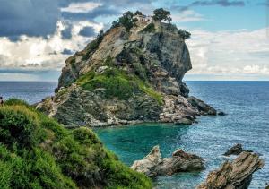 a small island in the ocean with a house on it at Mantos rooms 1 in Neo Klima