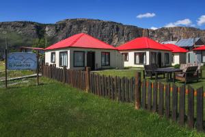 una fila de casas con techos rojos detrás de una valla en Cabañas El Puesto Sur en El Chaltén