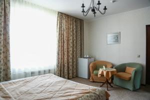 a bedroom with a bed and two chairs and a table at Vizit Hotel in Yekaterinburg