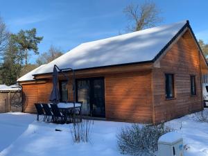 a wooden cabin with a table and chairs in the snow at Chalet Liquidambar in Zutendaal