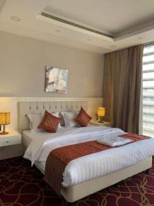 a bedroom with a large white bed with two lamps at Sokon Ladn Hotel in Riyadh