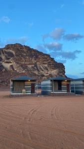 two buildings in the desert with a mountain in the background at Magic nature camp in Wadi Rum