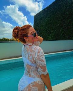 Una mujer con un vestido blanco parada junto a una piscina en Ezza in Barra - Beach Flat, en Recife