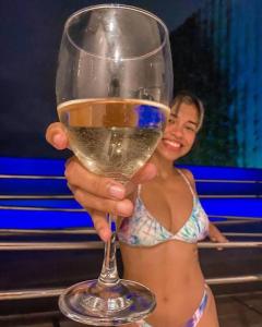 una mujer en bikini sosteniendo una copa de vino en Ezza in Barra - Beach Flat, en Recife