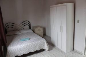 um quarto com uma cama com uma colcha branca em Pousada da Vovó (Nelci) em Ponta Grossa