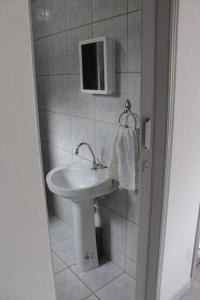 a white bathroom with a sink and a mirror at Pousada da Vovó (Nelci) in Ponta Grossa