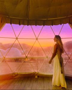 a woman in a white dress standing in front of a window at Rum Goldeneye luxury camp in Wadi Rum