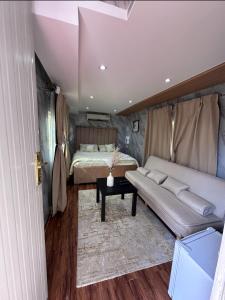 a bedroom with a bed and a couch and a table at Hatta Farm caravan in Hatta