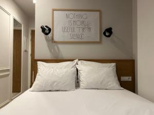 a bed with white pillows and a picture on the wall at Belle Athenes - Luxury Rooms at Monastiraki Railway Station in Athens