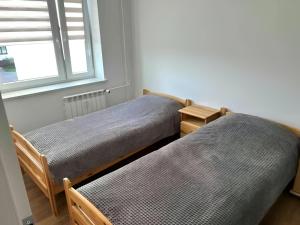 two beds in a room with a window at Augustòw Centre 1-Bedroom Comfort and Leisure. in Augustów