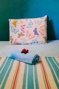 Una almohada con mariposas sentada en una cama en Eco chalés 1 e 2 en Cabo de Santo Agostinho