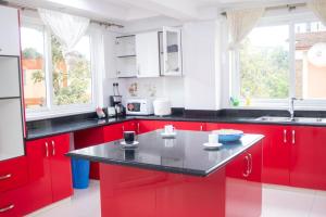 een keuken met rode kasten en een zwart aanrecht bij 4bedroom westlands raphta Nairobi in Nairobi