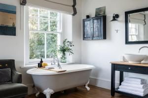 baño con bañera, lavabo y ventana en Devon Farmhouse en Kingsbridge