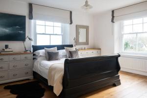 a bedroom with a bed and a dresser and two windows at Devon Farmhouse in Kingsbridge
