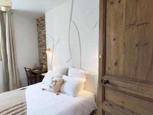 um quarto com uma cama com lençóis brancos e almofadas em Les Chambres D'Hespéris em Pleyben